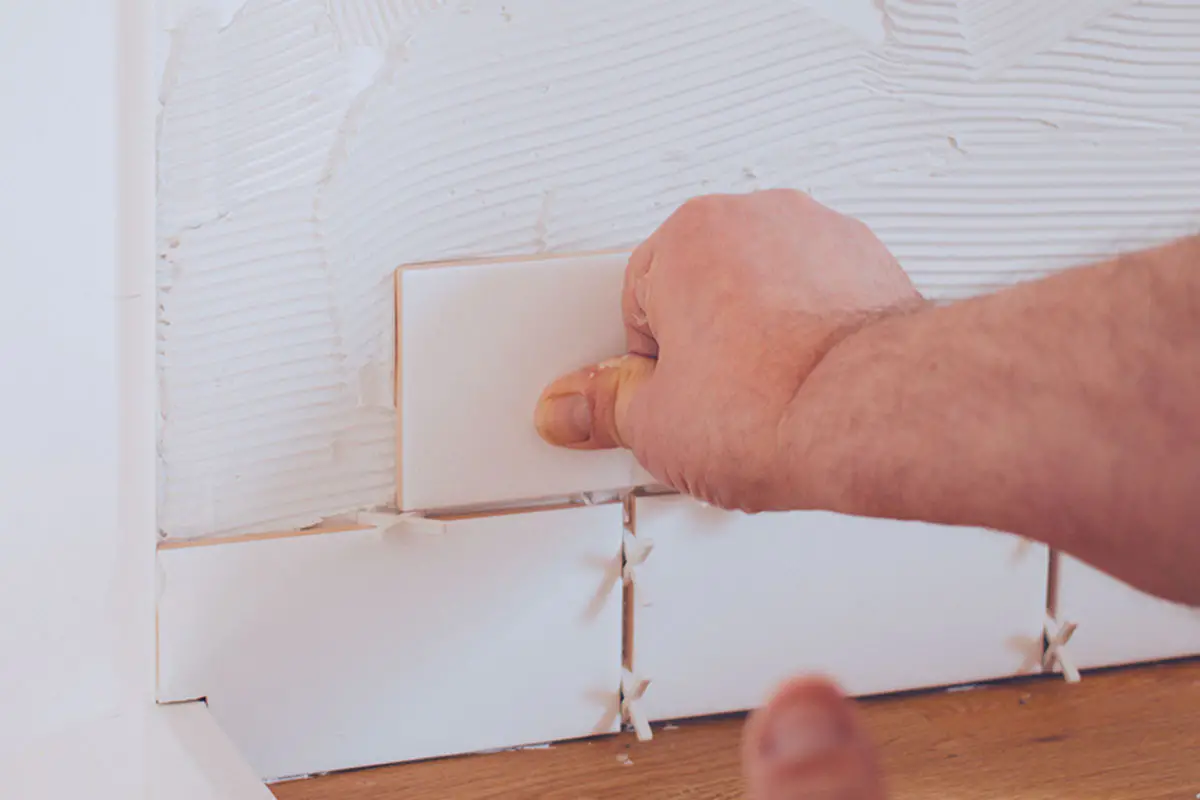 Man putting subway tile on wall